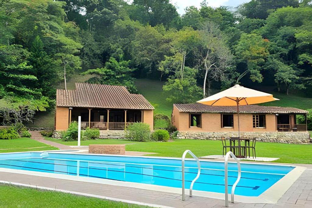 a house with a swimming pool in front of a house at Reserva tu casa rodeada de naturaleza en Villeta in Villeta
