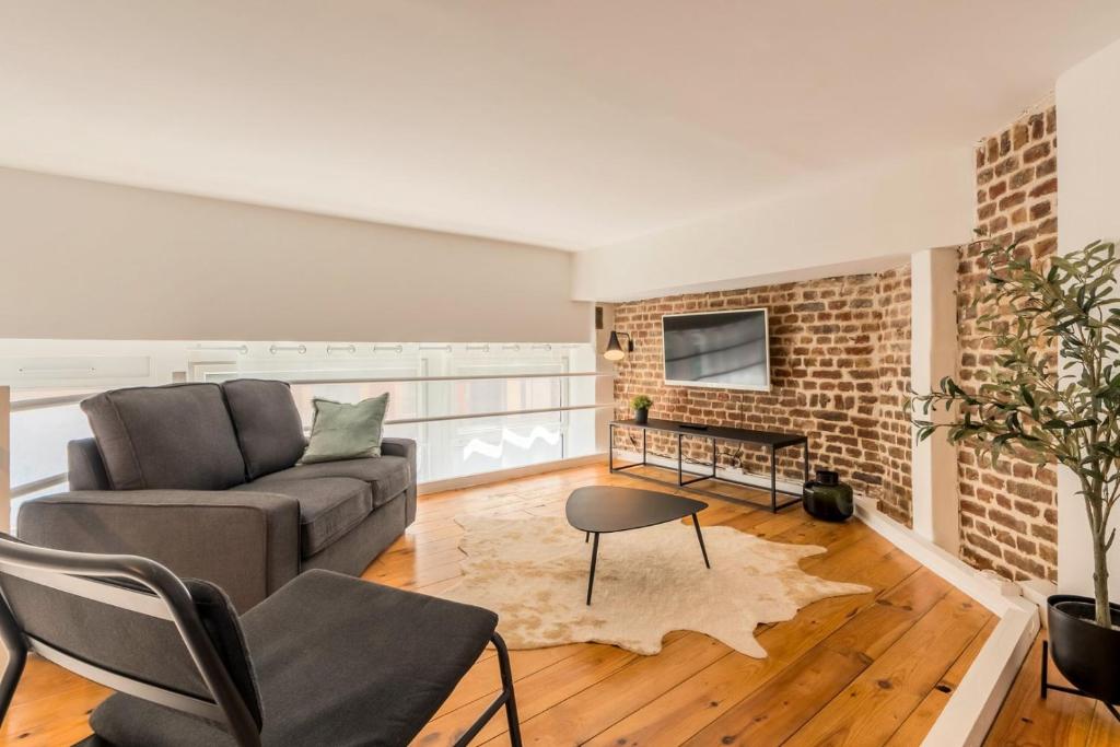 un salon avec un canapé et un mur de briques dans l'établissement Atypical flat in the centre of Lille., à Lille
