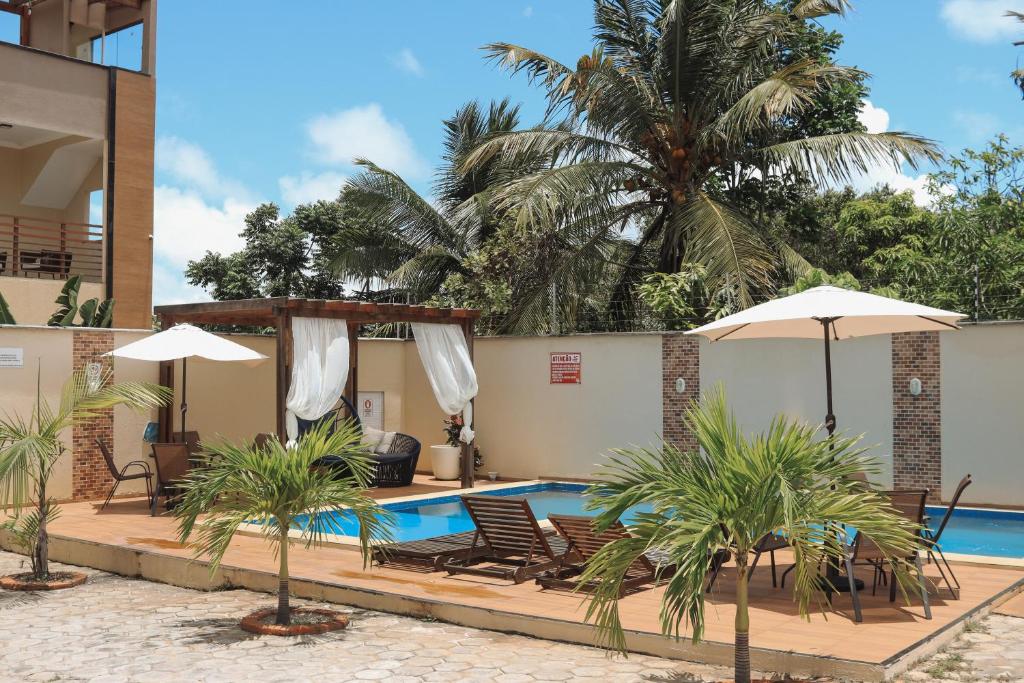 una piscina del resort con sedie, ombrelloni e una palma di POUSADA RECANTO DAS ÁGUAS Ville a Santo Amaro