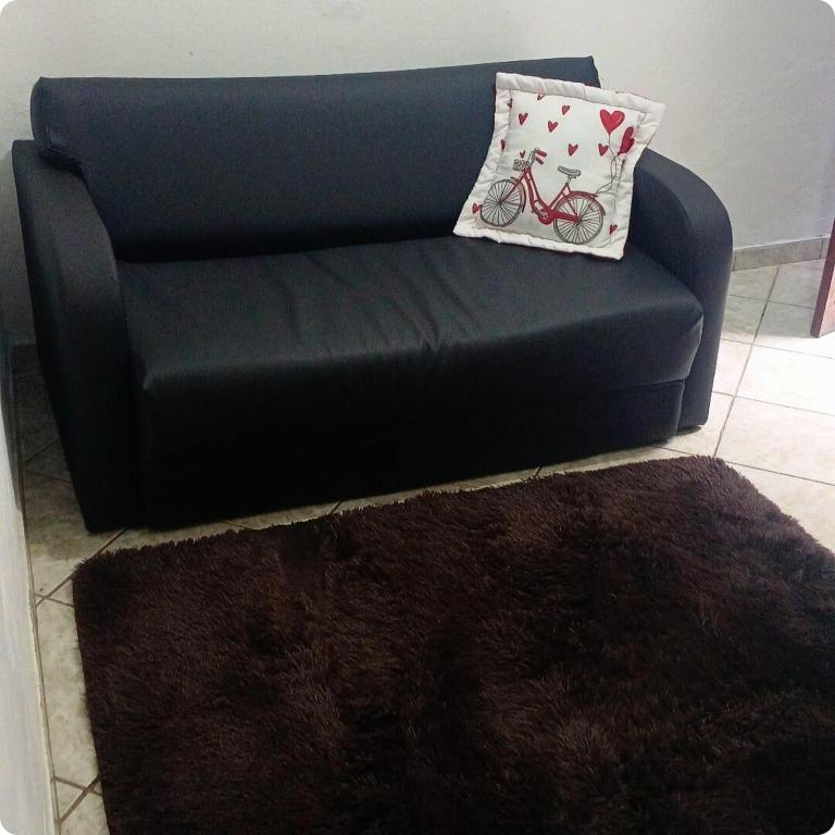 a black couch with a pillow with a bicycle on it at Casinha central Manhuaçu in Manhuaçu