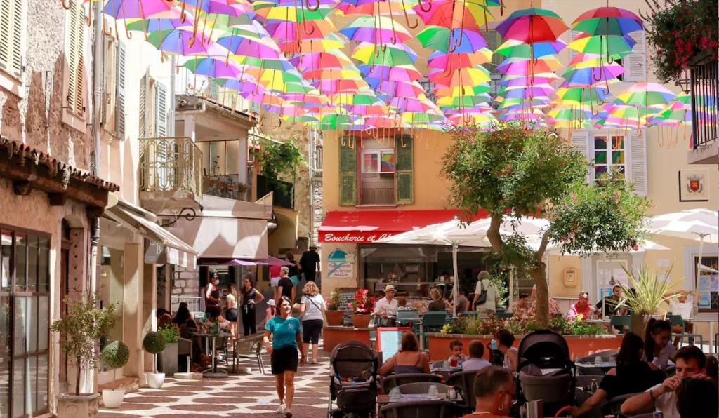 Un groupe de personnes marchant dans une rue avec des parapluies dans l'établissement Maison La Paillère, village, à Villeneuve-Loubet