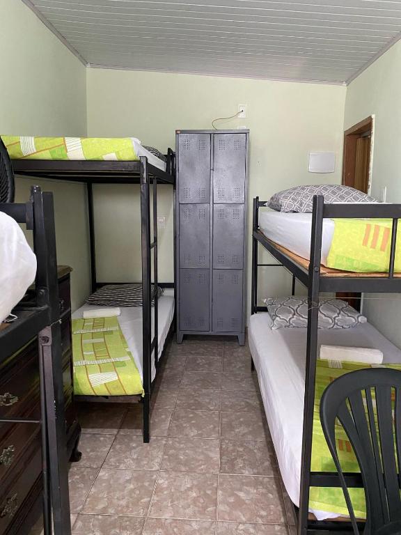Hotel Quarto em cobertura Santa Teresa ao lado da Glória, a dorm room with three bunk beds and a chair at Quarto em cobertura Santa Teresa ao lado da Glória in Rio de Janeiro