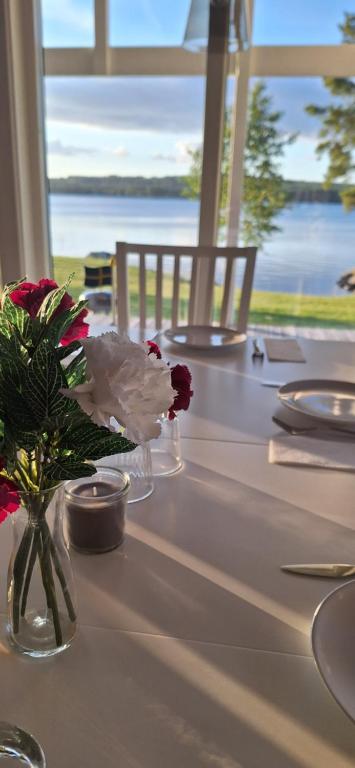 a table with flowers in a vase with a view of the ocean at Lakeview Houses Sweden in Falun