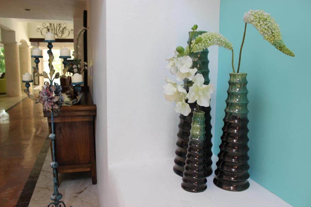 two vases with flowers in them on a wall at La Villa du Golf à Cancun Hotel Boutique in Cancún