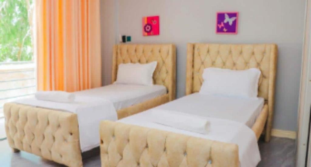 two beds in a room with orange curtains at Lovely room with balcony airy in Mombasa