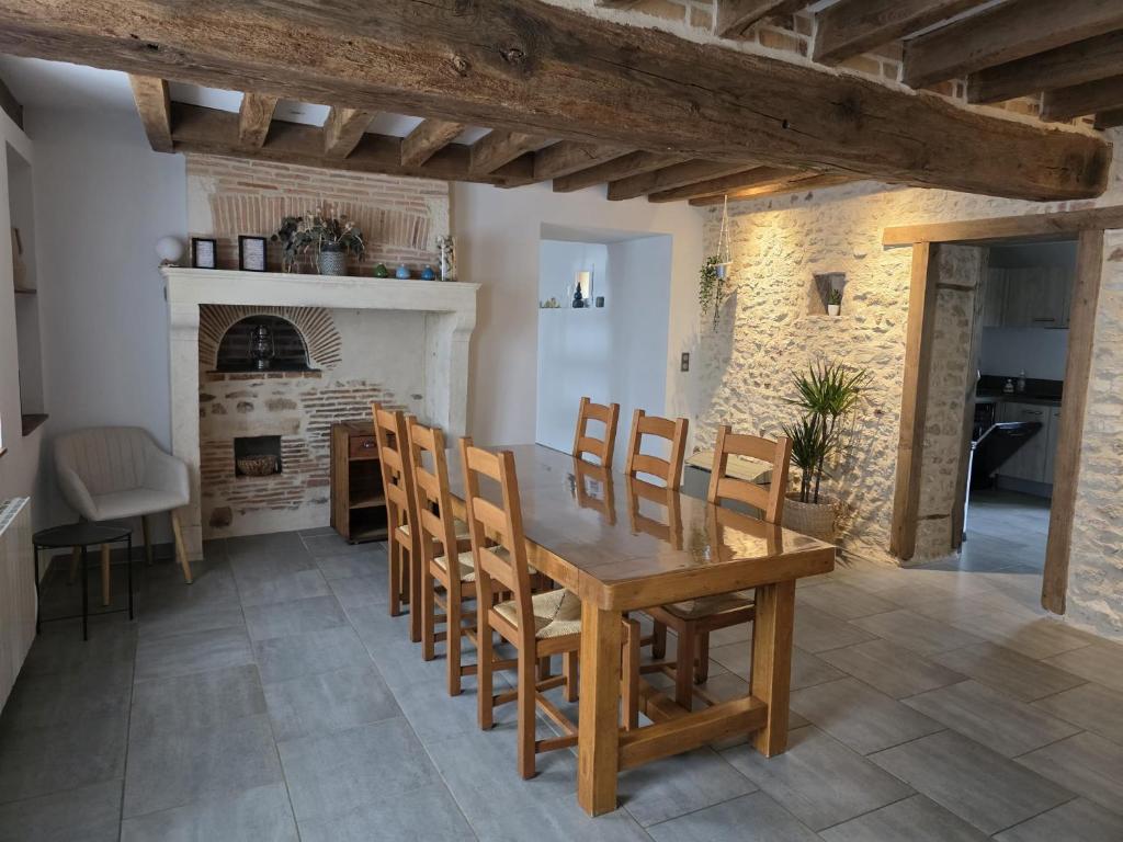 a dining room with a table and chairs and a fireplace at Gîte du Riou in Bué