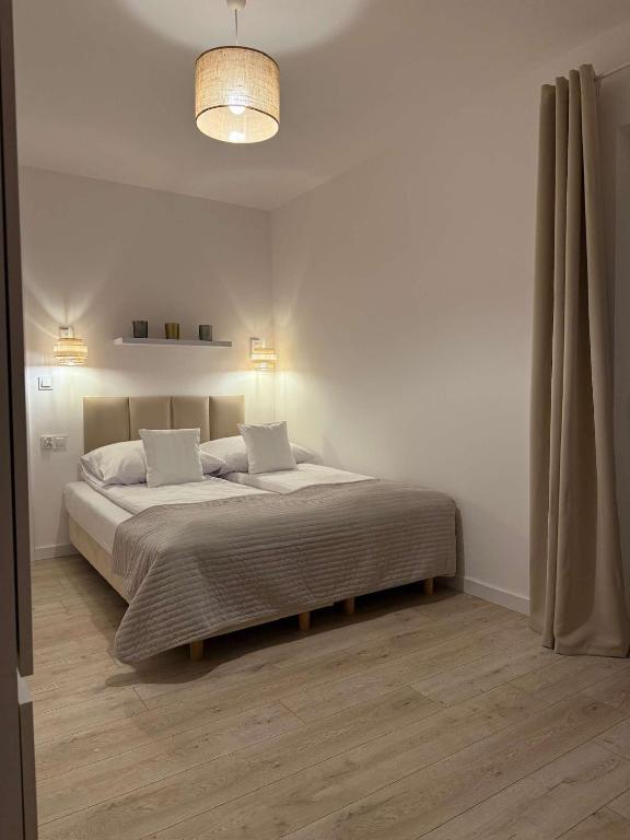 a white bedroom with a large bed with two pillows at Sportowa 10 in Jastarnia
