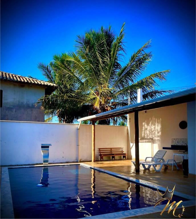 a house with a swimming pool and a palm tree at Apt Completo e Confortável 300mt Praia de Croa Vermelha in Coroa Vermelha