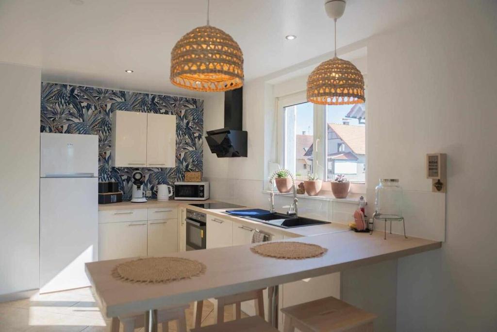 - une cuisine avec une table et deux lampes pendant dans l'établissement Le Cocon de l'Île, à Dalhunden