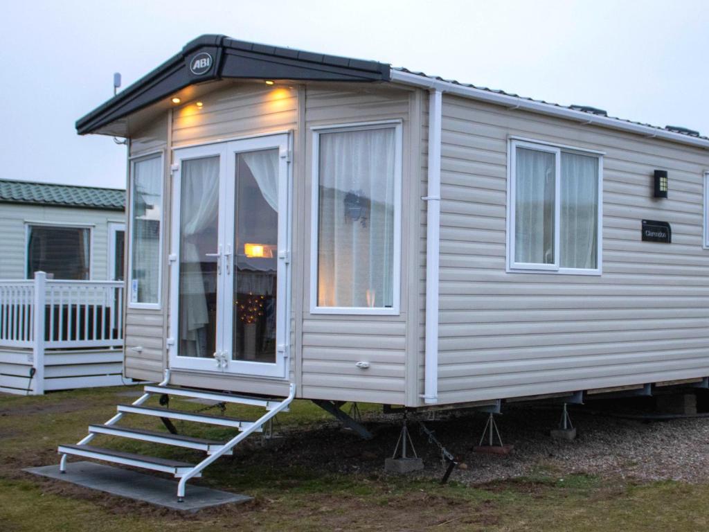 a white tiny house with a porch and stairs at Eagle's Den Caravan Holiday Retreat in Lossiemouth