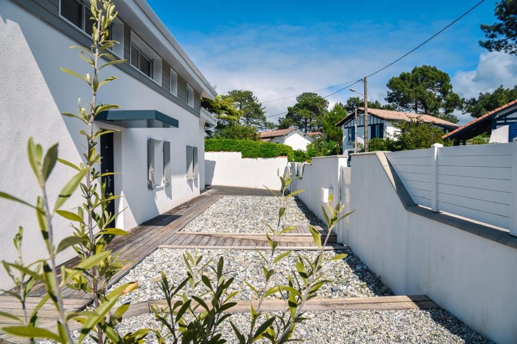 un jardin avec une allée à côté d'une clôture blanche dans l'établissement Villa contemporaine proximité plage et centre, à Capbreton