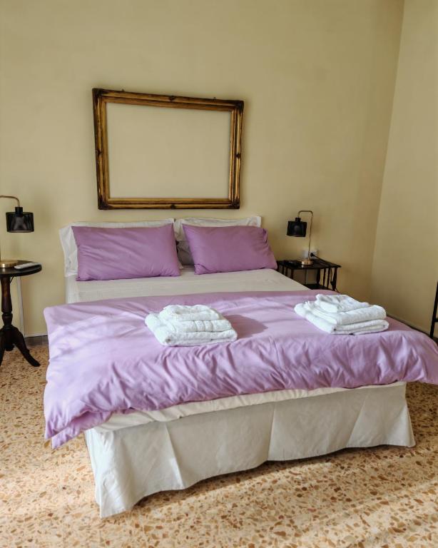 a bedroom with a purple bed with two towels on it at Le Cavallerizze in Caserta