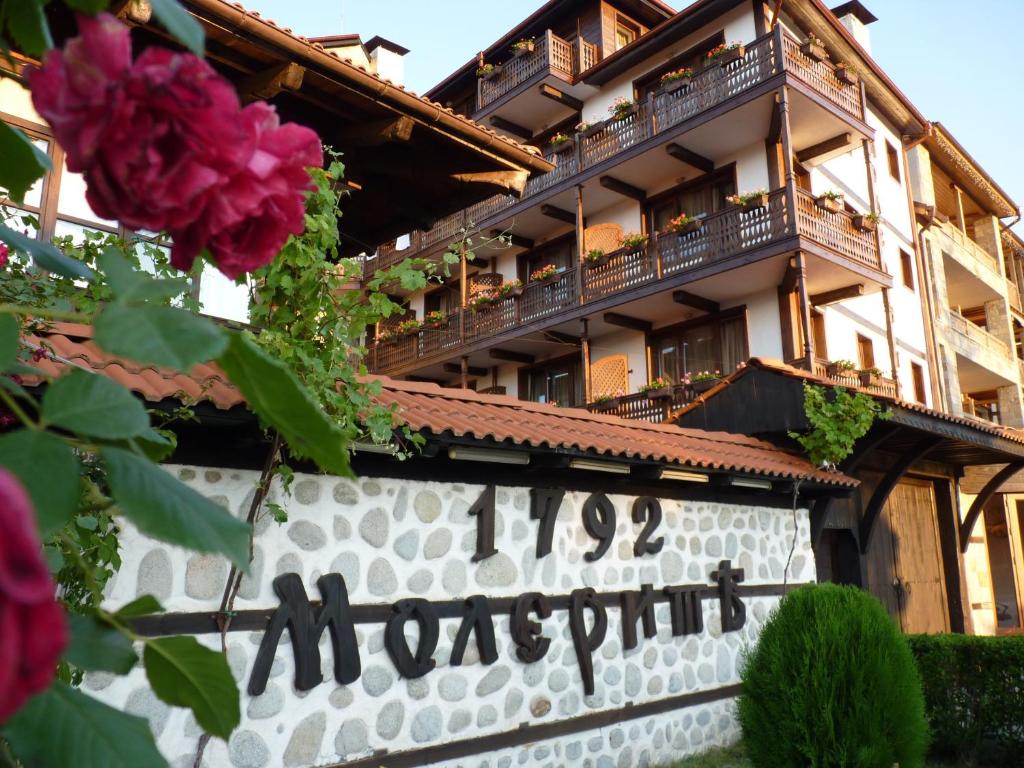 a sign in front of a building with flowers at Molerite Complex in Bansko