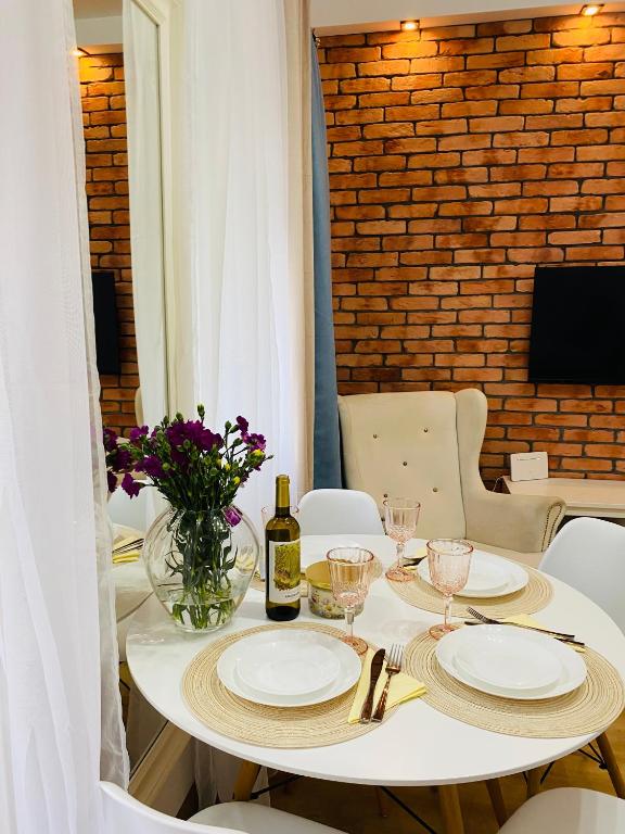 a white table with a bottle of wine and glasses at Przytulny apartament z tarasem in Olsztynek