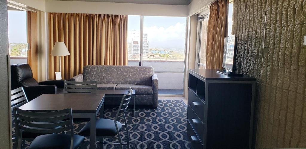 a hotel room with a couch and a table and a chair at Padre South Hotel On The Beach in South Padre Island