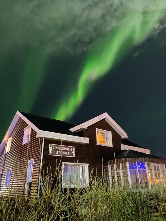 a house with the aurora in the sky at Guesthouse Lyngholt in Þórshöfn
