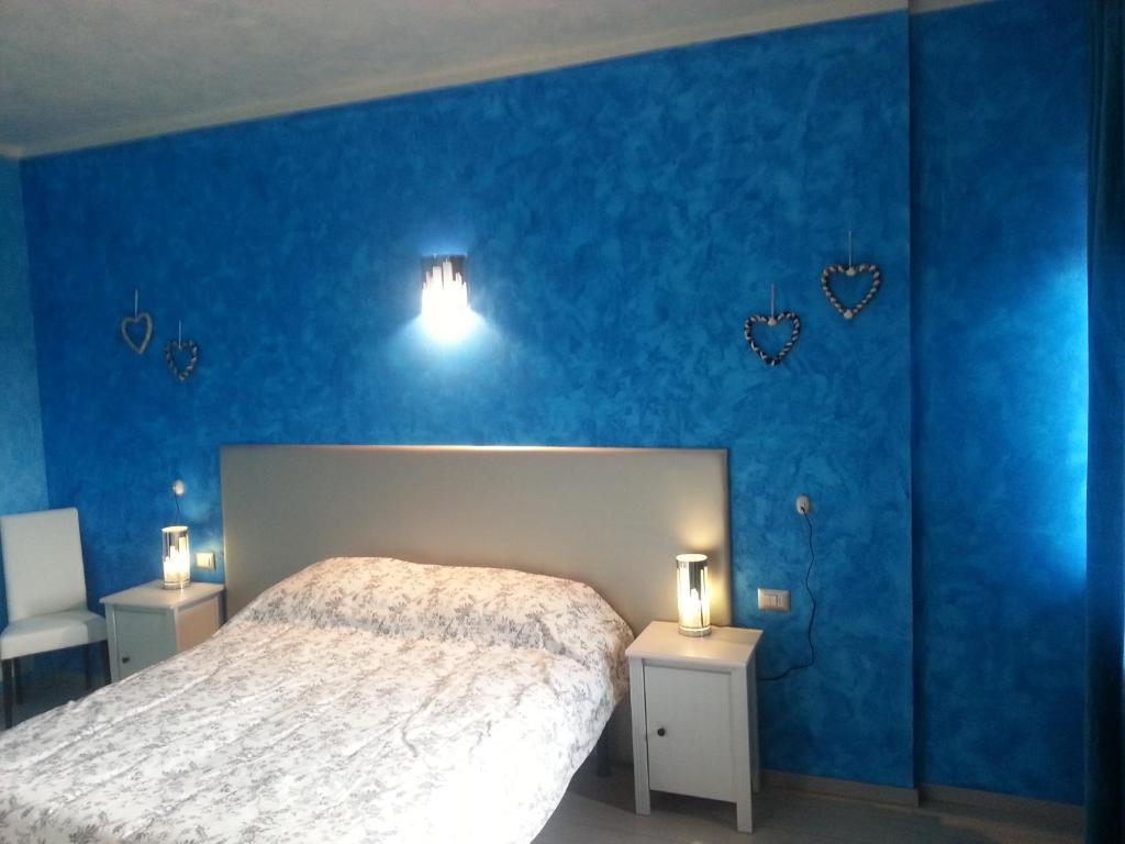 1 dormitorio con una pared azul, 1 cama y 2 luces en Fenix, en Fontanafredda