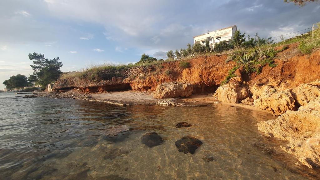 a house on the side of a cliff next to the water at Apartments by the sea Stara Novalja, Pag - 9396 in Novalja