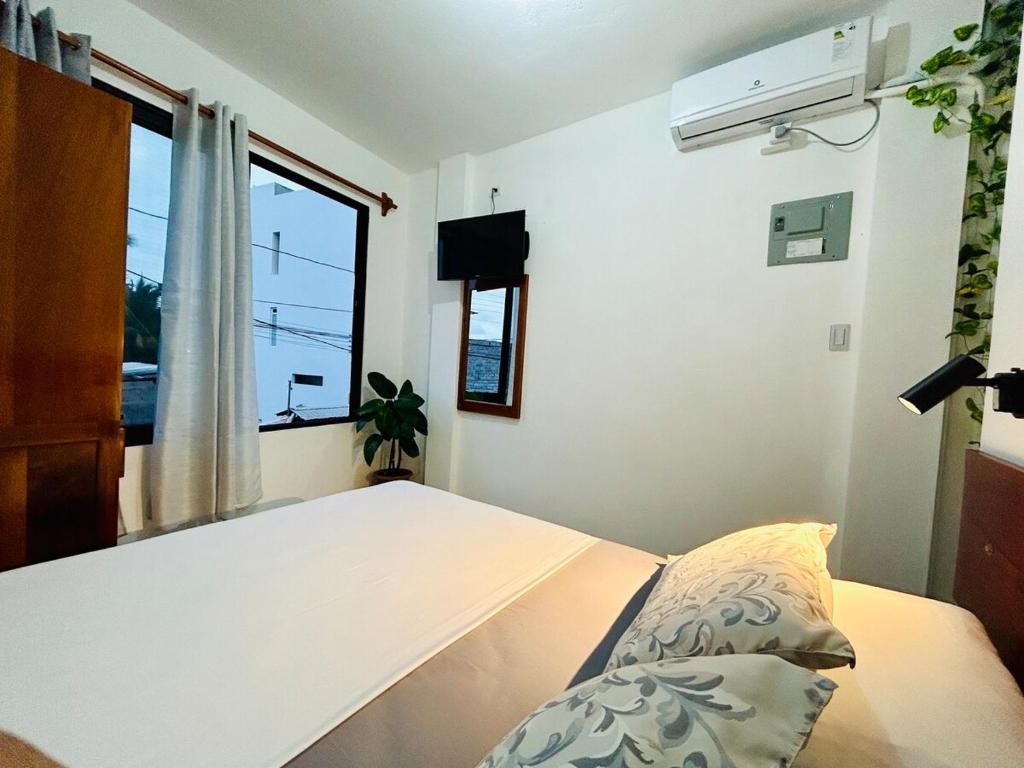 Un dormitorio con una cama blanca y una ventana. en Apartment with balcony and access to terrace, en Puerto Ayora