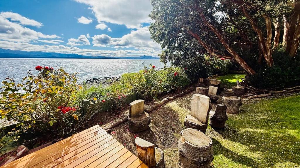 a wooden bench sitting next to a body of water at Departamento a Orilla del Lago in San Carlos de Bariloche