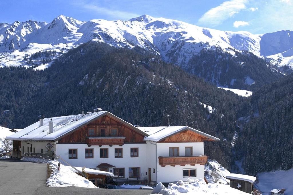 a house in the snow with mountains in the background at Alpengasthof Eppensteiner in Navis