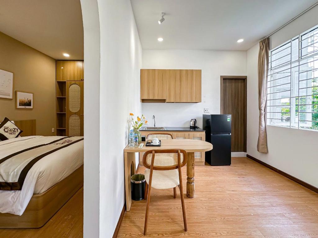 a bedroom with a bed and a table and a kitchen at The Cozy Nest in Ho Chi Minh City