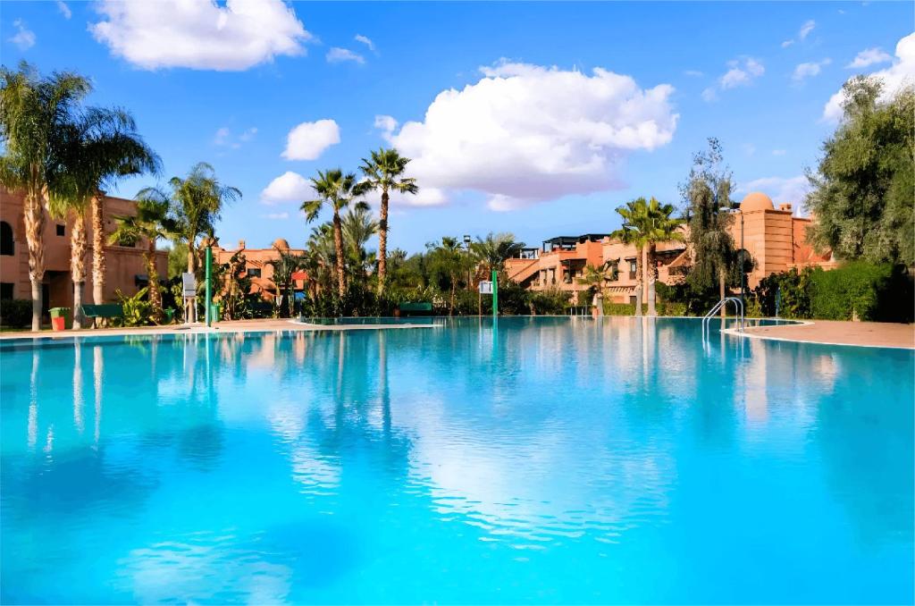 una gran piscina de agua azul con palmeras y edificios en Golden Palms Marrakech, en Marrakech