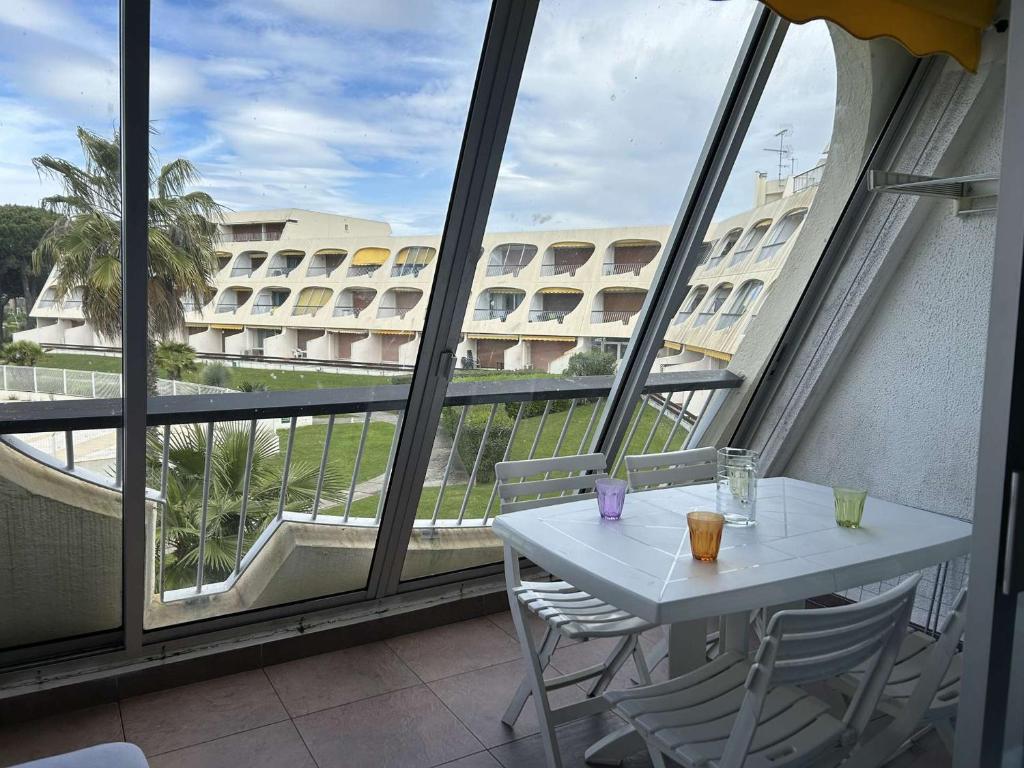 une table et des chaises sur un balcon avec vue sur un immeuble dans l'établissement Studio climatisé avec terrasse, 4 couchages, proche plage et commerces - FR-1-250-307, au Grau-du-Roi