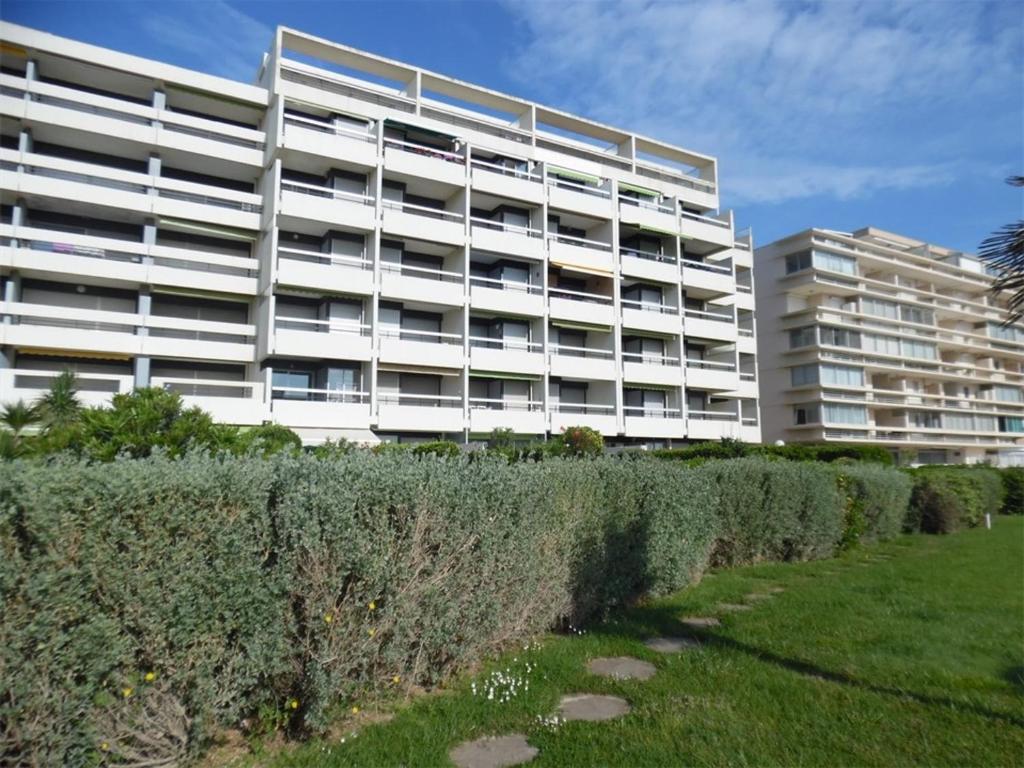 un grand bâtiment blanc avec une haie devant lui dans l'établissement Studio rénové pour 4 pers avec climatisation et parking, face mer - FR-1-750-73, à Canet