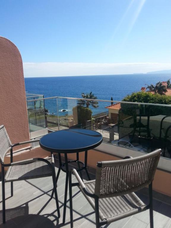 una mesa y sillas en un balcón con vistas al océano en Ventur Flat, en Caniço