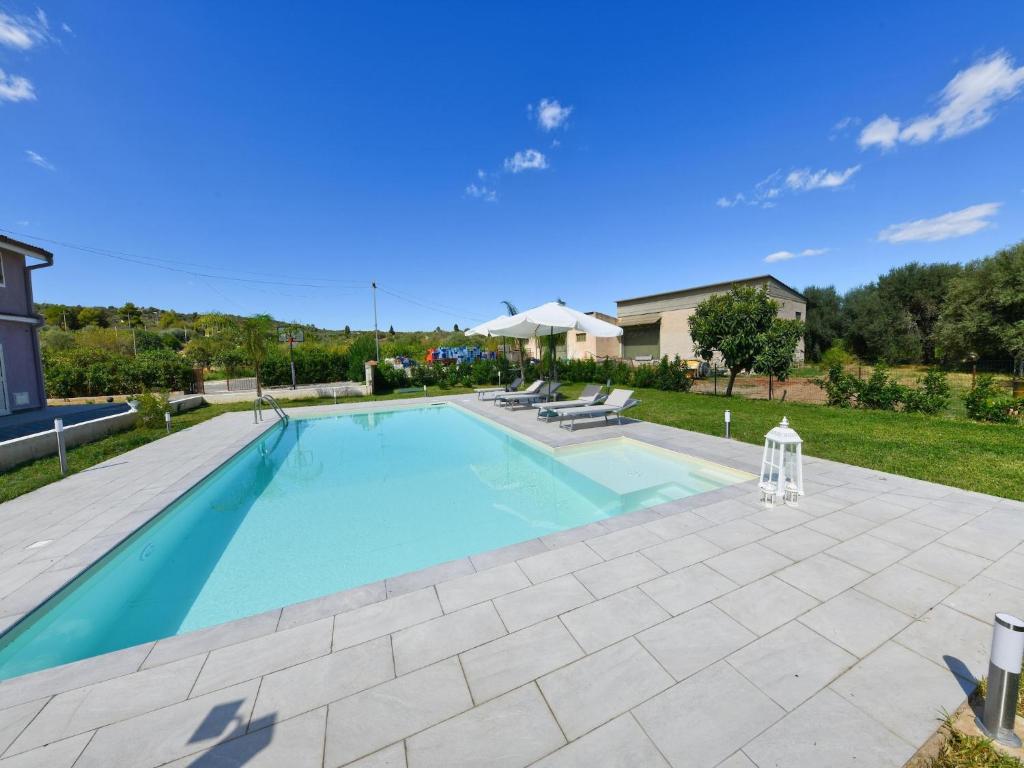 a large swimming pool in a yard with a patio at Villa with private pool in Floridia