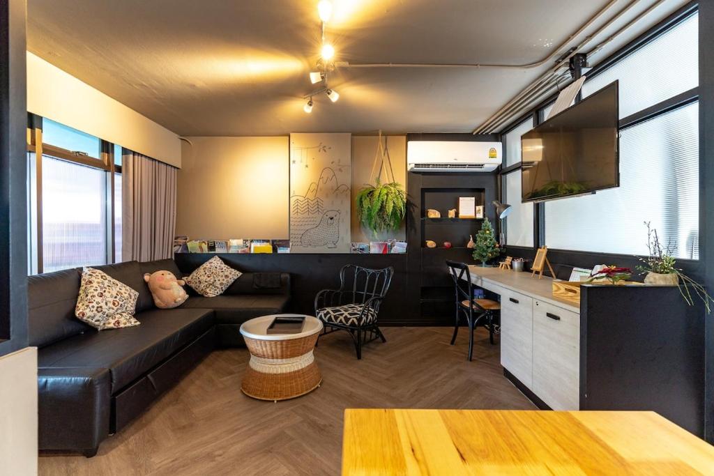 a living room with a black couch and a kitchen at Thip Residence at Surawong in Bang Rak