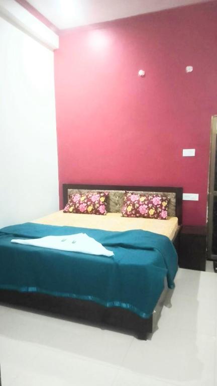 Un dormitorio con una cama con una pared roja. en Kishan guest house, en Ayodhya