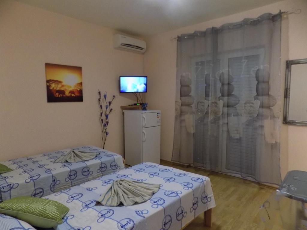 a bedroom with two beds and a tv on the wall at Apartments Las Cabezas in Zadar