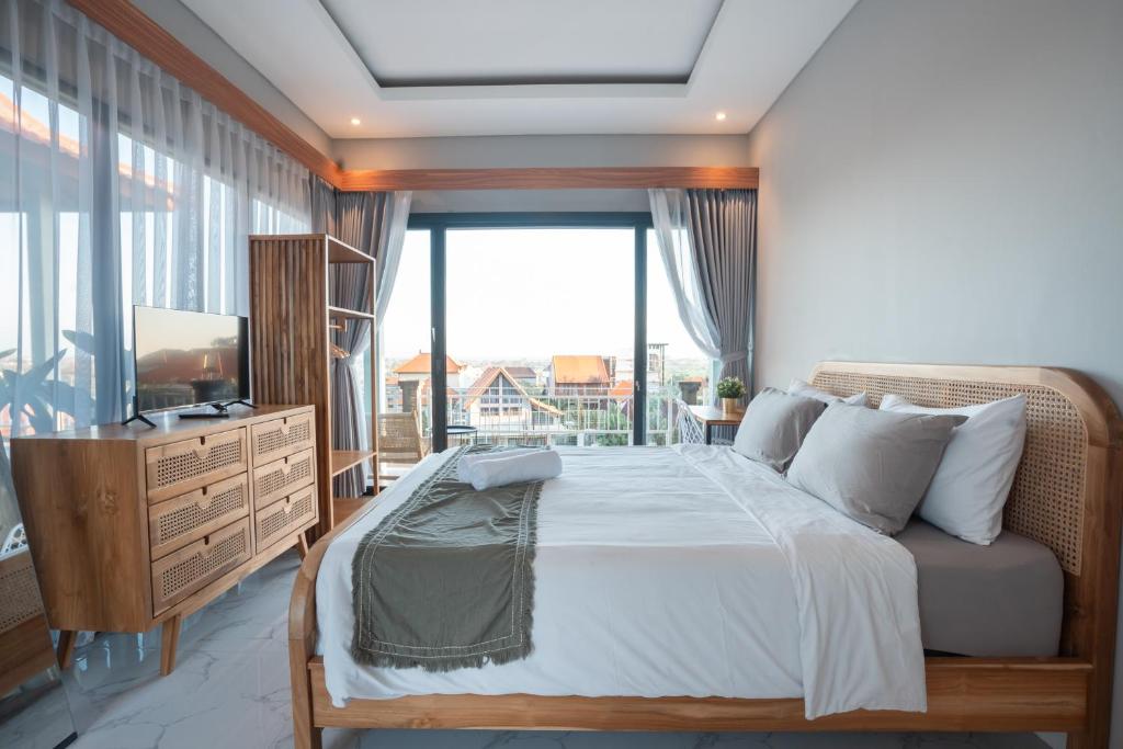 a bedroom with a bed and a large window at Navee Studio Apartments Canggu in Munggu