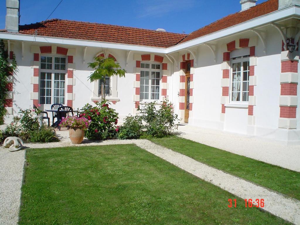 une maison blanche et rouge avec une cour verte dans l'établissement Villa des trois Statues, à Arcachon