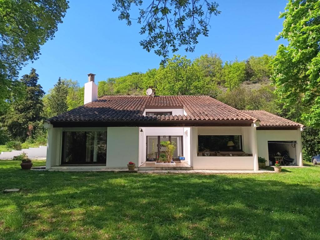 a small white house with a green yard at Maison de campagne avec lac privé in Fendeille