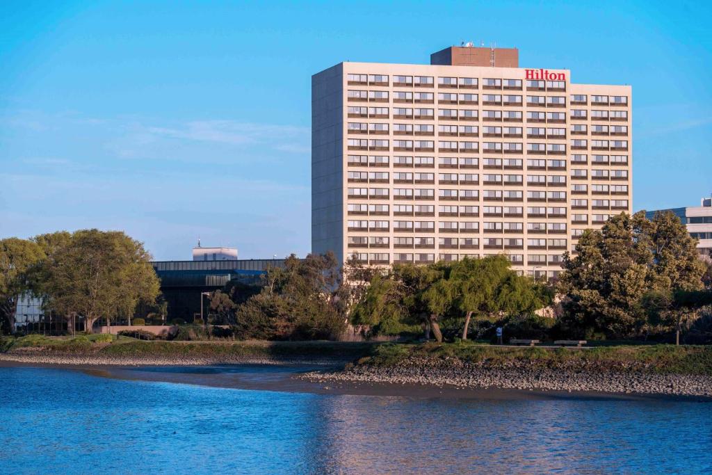 un edificio de hotel junto a un cuerpo de agua en Hilton San Francisco Airport Bayfront - No Resort Fee, en Burlingame