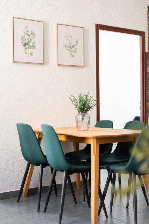 une salle à manger avec une table en bois et des chaises vertes dans l'établissement Nîmes centre, à Nîmes