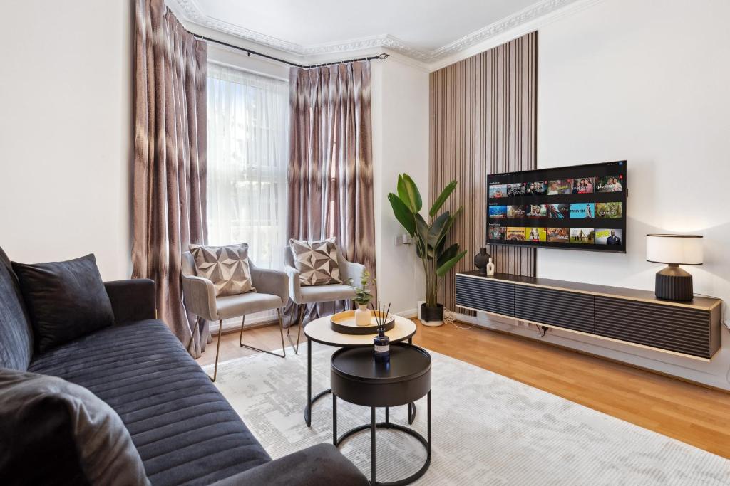 a living room with a couch and a tv at North London 4-Bed House, Garden, Shops & Tube Nearby in New Southgate