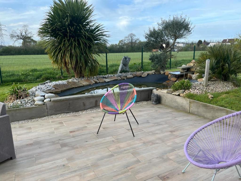 deux chaises violettes assises sur une terrasse avec un étang dans l'établissement Maison, à Bolleville
