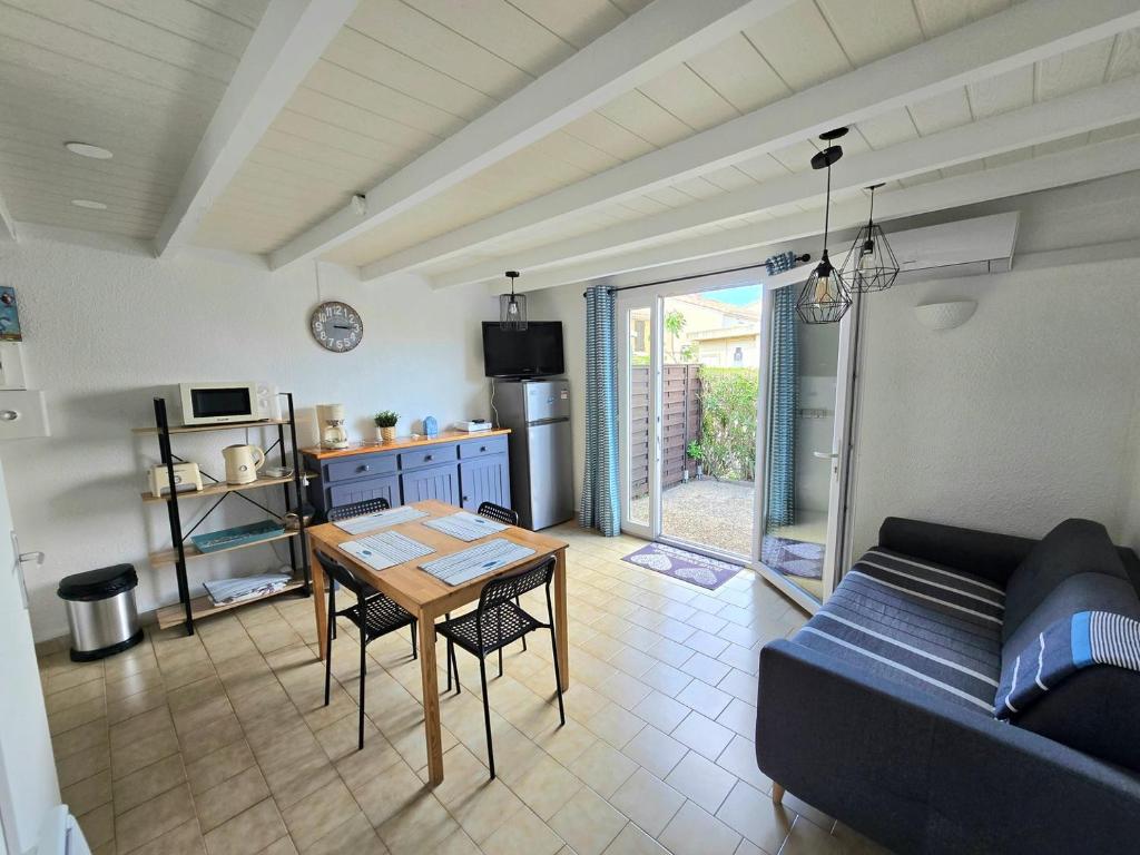 un salon avec une table et un canapé dans l'établissement SANTOLINES : Charmante maisonnette avec piscine proche Etang, à Marseillan