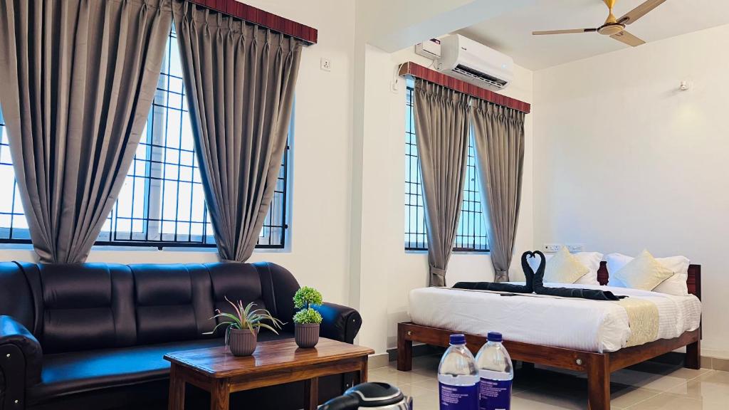 a bedroom with a bed and a couch and windows at The Plaza - 100 feet Road, Near Indira Gandhi Statue, Pondicherry - JR Groups in Puducherry