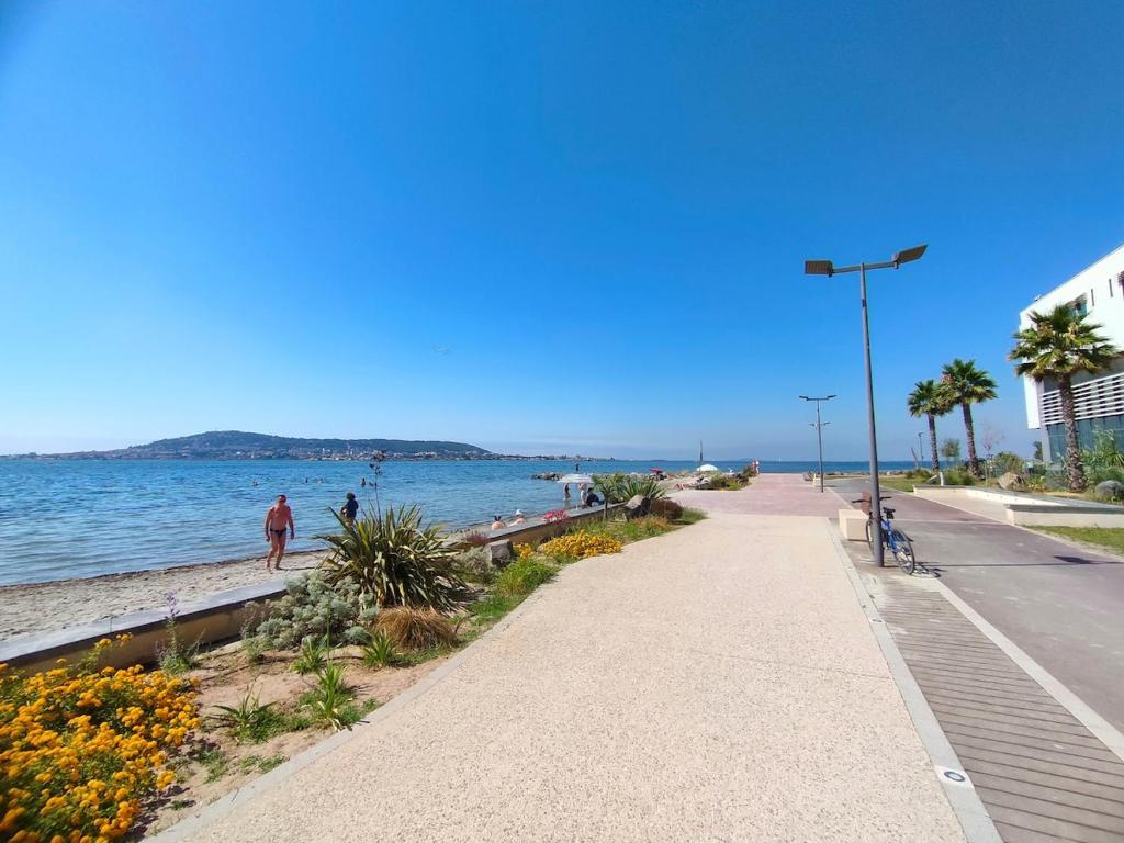 un trottoir à côté de l'océan avec des gens qui marchent sur la plage dans l'établissement SEVIGNE 5 : Repos et tranquillité à deux pas des thermes, à Balaruc-les-Bains