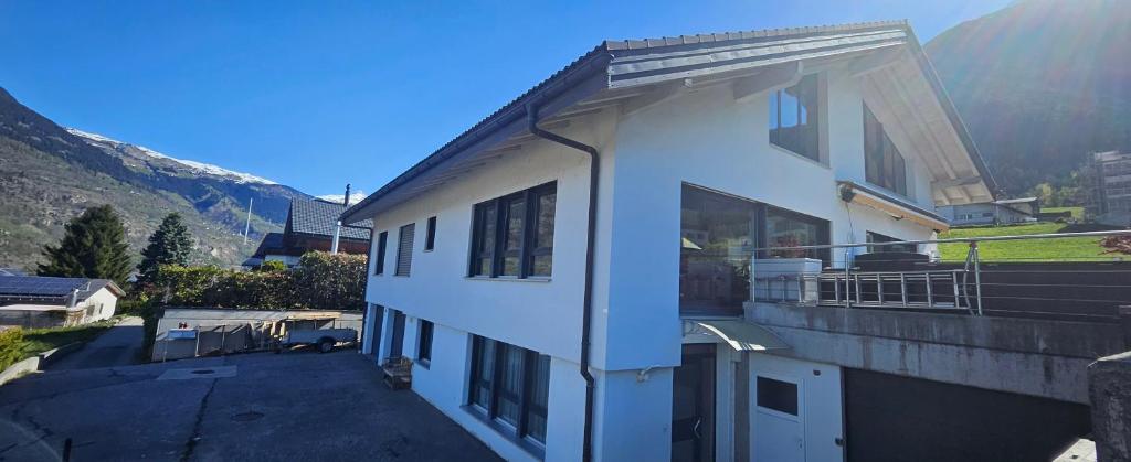 a white building with a balcony with mountains in the background at Ferienwohnung Bergweg in Termen