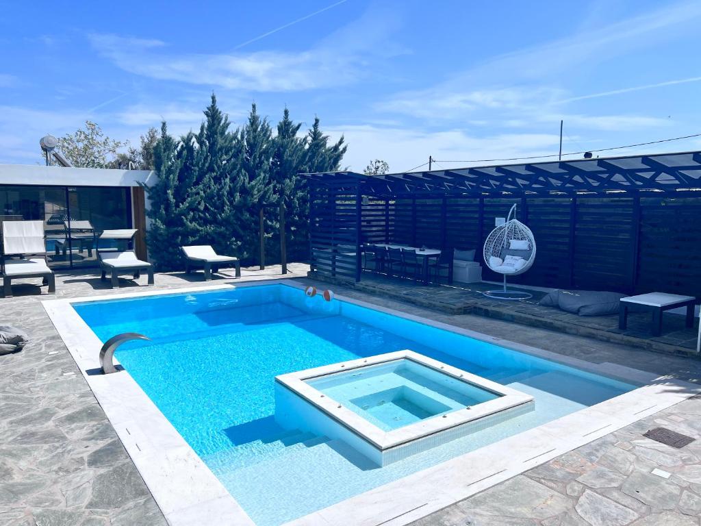 a swimming pool with blue water in a yard at Olivujoj Villajoj - Deluxe Villa with Detached Pool House in Anavyssos