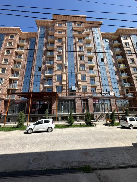 two cars parked in front of a large building at ONE GLOBAL FAMILY GUEST HOUSE SAMARKAND lll in Samarkand