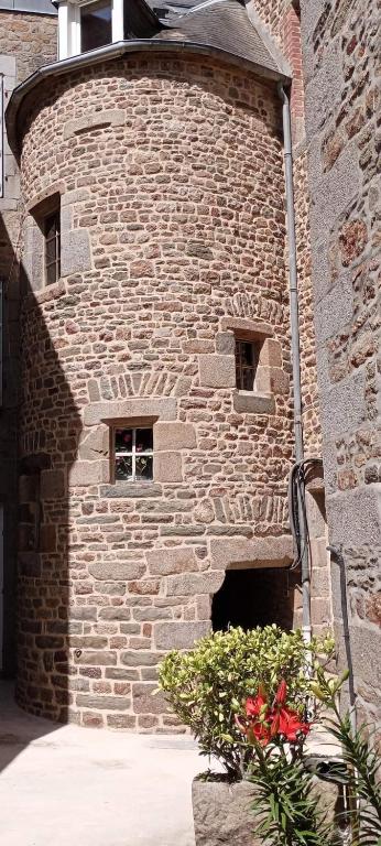 un mur de briques avec deux fenêtres dans un bâtiment dans l'établissement Cour historique La cour des trois rois 1, à Villedieu-les-Poêles