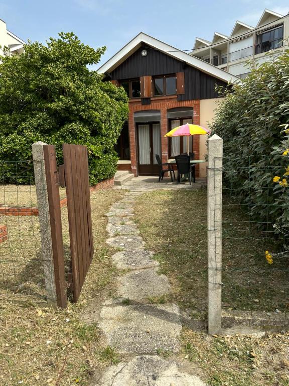 une maison avec une clôture et une table avec un parasol dans l'établissement Caprice, à Lacanau-Océan