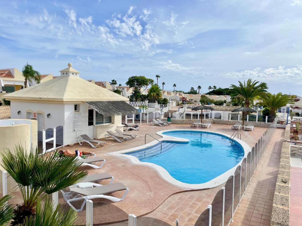 a swimming pool with lounge chairs and a resort at Bungalow Golf del Sur in San Miguel de Abona